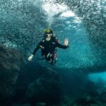 A scuba diver exploring the spectacular Serenggeh Canyon while surrounded by millions of fish in the Perhentian Islands