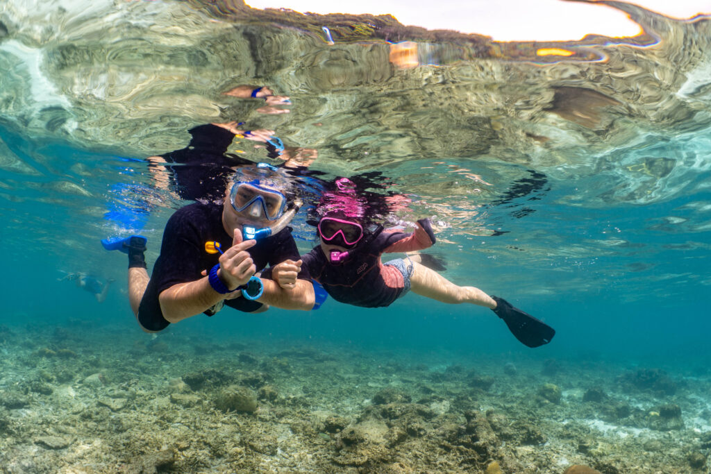 happy couple snorkelling in the crystal clear waters of the Perhentian Islands while a YBD team photographer captures their holiday memories.